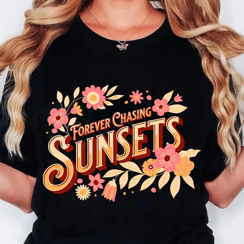 May include: Black t-shirt with the text "Forever Chasing Sunsets" in a retro font, adorned with pink and yellow floral accents. The design features a vintage aesthetic, perfect for casual wear.