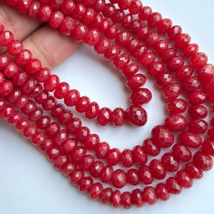 May include: Strands of faceted, deep red gemstone beads. The beads are small, with a rounded, teardrop shape and a sparkling, polished finish. The beads are strung together, forming multiple strands of a necklace or bracelet.
