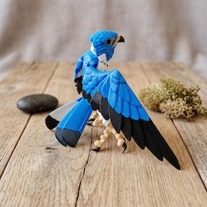 May include: A detailed, blue and black bird figurine with outstretched wings. The bird has a textured surface, white accents, and a realistic beak and talons. The figurine is posed on a wooden surface, suggesting a decorative item or collectible.