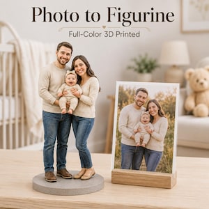 May include: A full-colour 3D printed figurine of a family of three standing on a circular grey base, accompanied by a rectangular photograph of the same family in a wooden stand. The text Photo to Figurine and Full-Colour 3D Printed is visible.