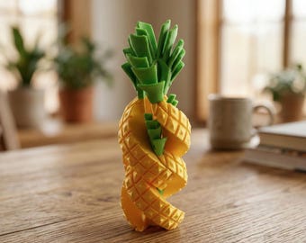 May include: A yellow and green pineapple-shaped decorative object. The pineapple has a spiral design with a textured surface. The top of the pineapple features green leaves. The object is on a wooden table.