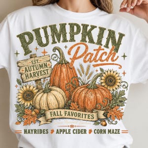 May include: A white t-shirt featuring a graphic with the text PUMPKIN Patch, EST. AUTUMN HARVEST, FALL FAVORITES, and HAYRIDES APPLE CIDER CORN MAZE. The design includes orange pumpkins, yellow sunflowers, wheat stalks, and autumn leaves.