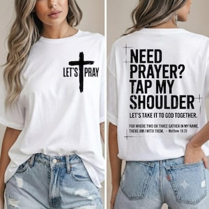 Könnte beinhalten: Ein weißes T-Shirt mit einer schwarzen Kreuzgrafik und dem Text "LET'S PRAY" auf der Vorderseite. Die Rückseite zeigt den Text "NEED PRAYER? TAP MY SHOULDER. LET'S TAKE IT TO GOD TOGETHER. FOR WHERE TWO OR THREE GATHER IN MY NAME, THERE AM I WITH THEM. - MATTHEW 18:20."