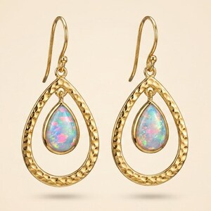 May include: A pair of gold-toned drop earrings featuring a hammered teardrop frame. Suspended within each frame is a smaller, pear-shaped iridescent opal cabochon. The earrings are attached to simple gold-toned ear wires for secure hanging.