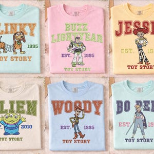 Può includere: Sei magliette colorate di Toy Story con diversi personaggi: Slinky, Buzz Lightyear, Jessie, Alien, Woody e Bo Peep. Ogni maglietta ha il nome del personaggio in un font universitario, l'anno di uscita del film e le parole "Toy Story".