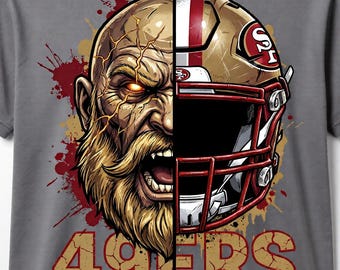 May include: Gray t-shirt featuring a split design: one side depicts a fierce warrior with a golden beard and glowing eyes, the other a gold and red football helmet. The text "49ERS" is displayed in gold.