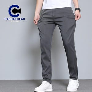 May include: Gray casual pants with a straight leg fit. The pants are shown with a white t-shirt and white sneakers. The logo "CASUALWEAR BYPAOLO" is in the upper left corner. The pants are made of a smooth, wrinkle-resistant fabric.