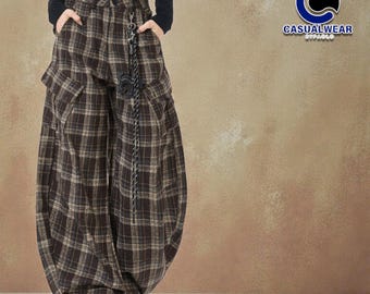 May include: Brown plaid wide-leg pants with large pockets. The pants have a unique, voluminous shape and a decorative chain detail. The Casualwear logo is visible in the upper right corner. The pants are made of a soft, comfortable material.