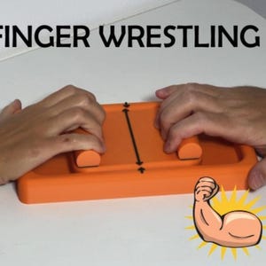 Può includere: Un gioco di finger wrestling arancione con la scritta "FINGER WRESTLING" in alto. Il gioco ha due cilindri arancioni per le dita. Una linea nera con frecce è al centro. Un braccio di cartone animato che si flette è in basso a destra.