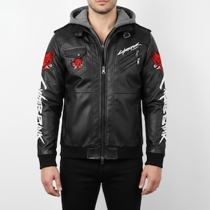 Könnte beinhalten: Schwarze Kunstlederjacke mit grauem Kapuzeneinsatz. Mit roten Teufel-Patches, weißem Text auf den Ärmeln und dem Wort "Cyberpunk" in weißer Schrift. Mit Reißverschluss und mehreren Taschen.