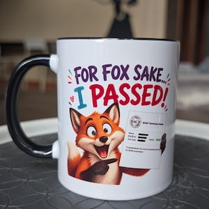 May include: A white ceramic mug with a black handle and rim, featuring a cartoon fox pointing at a BACB examination results document. The text reads "FOR FOX SAKE... I PASSED!" in purple and red lettering, with small colorful decorative accents.
