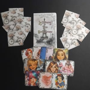 May include: A collection of decorative items, including a notebook with the text "Le Mémoire Des Budgeteuses" and illustrations of the Eiffel Tower, along with several square cards featuring bicycle and floral designs, and portraits of various characters.