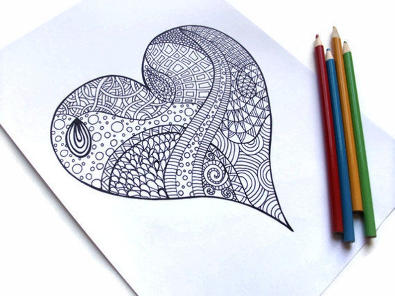 May include: A detailed black and white heart-shaped drawing with intricate patterns, including geometric shapes, swirls, and dots. Colored pencils in red, blue, yellow, and green are arranged beside the drawing on a white surface.