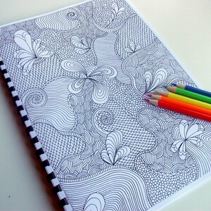 Peut inclure: Un cahier &agrave; spirales avec un motif de gribouillis abstrait en noir et blanc. Le cahier est accompagn&eacute; d'un ensemble de six crayons de couleur rouge, orange, jaune, vert et bleu.