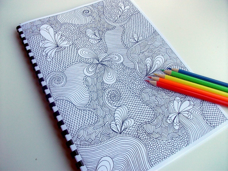 Peut inclure: Un cahier &agrave; spirales avec un motif de gribouillis abstrait en noir et blanc. Le cahier est accompagn&eacute; d'un ensemble de six crayons de couleur rouge, orange, jaune, vert et bleu.