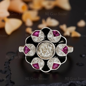 Peut inclure: Une bague de style vintage avec une pierre centrale ronde et transparente entourée d'un motif floral en émail noir. La fleur comporte six pétales, chacun orné d'une pierre rose et de petits diamants blancs. La monture de la bague est argentée.