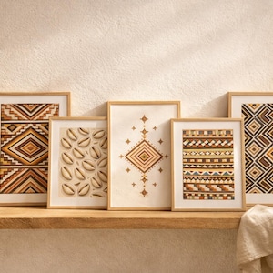 May include: Five framed art prints with geometric and natural designs. The prints feature patterns in shades of brown, beige, and orange. One print displays seashells. The frames are light brown, and the artwork is displayed on a wooden shelf.