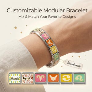 May include: A customizable modular bracelet with colorful zodiac sign charms. The bracelet is shown on a wrist, with additional charms displaying the months of March and April. The charms are square and feature various designs and colors.
