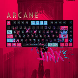 以下が含まれることがあります： 「ARCANE」の文字が金色で描かれた、カスタムキーキャップ付きの黒いメカニカルキーボード。キーボードには青とピンクのアクセントがあり、下部にはピンクと青で「JINX」という名前が書かれています。背景は濃い赤色です。