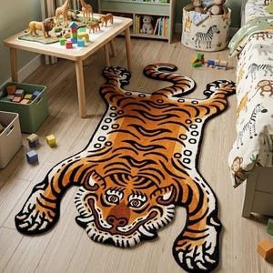 Könnte beinhalten: Ein tigerförmiger Teppich mit einem lebendigen orangefarbenen, schwarzen und weißen Streifenmuster. Der Teppich ist einem Tiger nachempfunden, mit einem detaillierten Gesicht, vier ausgestreckten Pfoten und einem langen Schwanz, flach auf einem hellen Holzboden.