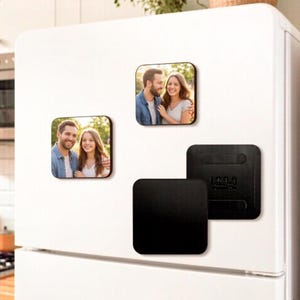 May include: Square photo magnets with rounded corners, showing a couple in a natural setting. The magnets are on a white fridge door, with a black magnet visible.