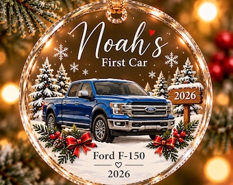 May include: A circular clear acrylic ornament featuring a blue Ford F-150 pickup truck in a snowy forest. Text reads Noah's First Car, Ford F-150, and 2026. The design includes snowflakes, a wooden sign with 2026, red bows, and holly berries.