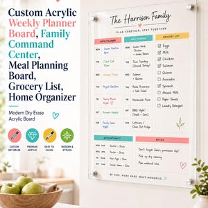 May include: A clear acrylic weekly planner board mounted on a wall with silver hardware. The board features sections for a weekly planner, meal planner, grocery list, appointments, and notes, with text reading The Harrison Family and Plan Together, Stay Together.