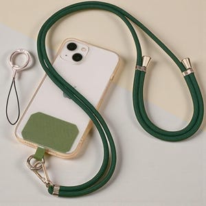 May include: A clear phone case with a green strap and a matching green patch. The strap is a dark green cord with gold-coloured metal accents and a silver-coloured clasp. A silver-coloured ring is also included.