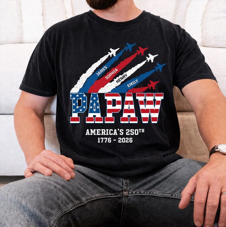May include: Black t-shirt with a patriotic design. The word "PAPAW" is displayed in red, white, and blue, with the text "AMERICA'S 250TH 1776 - 2026" below. Above, four jets leave trails with names: James, Sophia, Henry, and Emily.