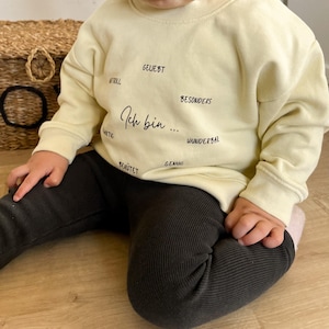 Könnte beinhalten: Set aus drei Keramikbechern mit gesprenkelter, matter Oberfläche. Die Becher sind in Creme-, Hellgrau- und Dunkelgrautönen gehalten. Jede Tasse hat ein schlichtes, minimalistisches Design.