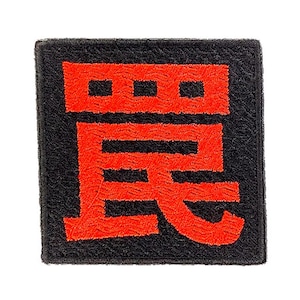 以下が含まれることがあります： 黒い背景に鮮やかな赤色の日本語の漢字が中央に刺繍された正方形のワッペン。刺繍は質感のある立体的な仕上がりで、正方形の縁にははっきりとした境界線が施されています。