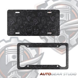 May include: Black license plate and frame featuring a repeating pattern of cartoon characters in white outlines. The license plate has three holes for mounting. The frame has four holes. The text "AUTOGEAR STUDIO" is at the bottom.