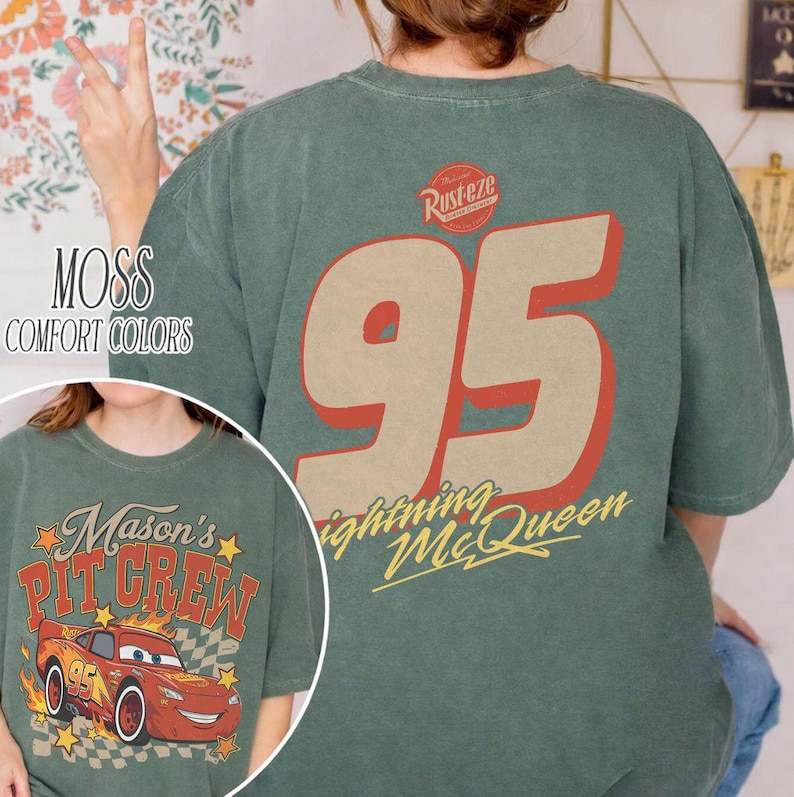 Op de afbeelding: Een mosgroen t-shirt met een grote afbeelding op de achterkant met het nummer 95 in beige met een rode omlijning, het Rust-eze logo en de tekst Lightning McQueen. De voorkant toont een rode raceauto met de tekst Mason's Pit Crew.