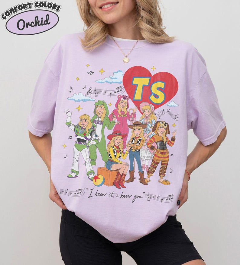 Puede incluir: Una camiseta de color morado claro con un estampado gr&aacute;fico de siete personajes disfrazados, un gran coraz&oacute;n rojo con las letras amarillas TS, notas musicales y el texto I knew it, i knew you en una fuente cursiva.