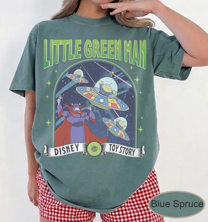 May include: A blue spruce t-shirt with a Disney Toy Story graphic. The design features the text "Little Green Man" above a scene with aliens in flying saucers and the character Zurg.
