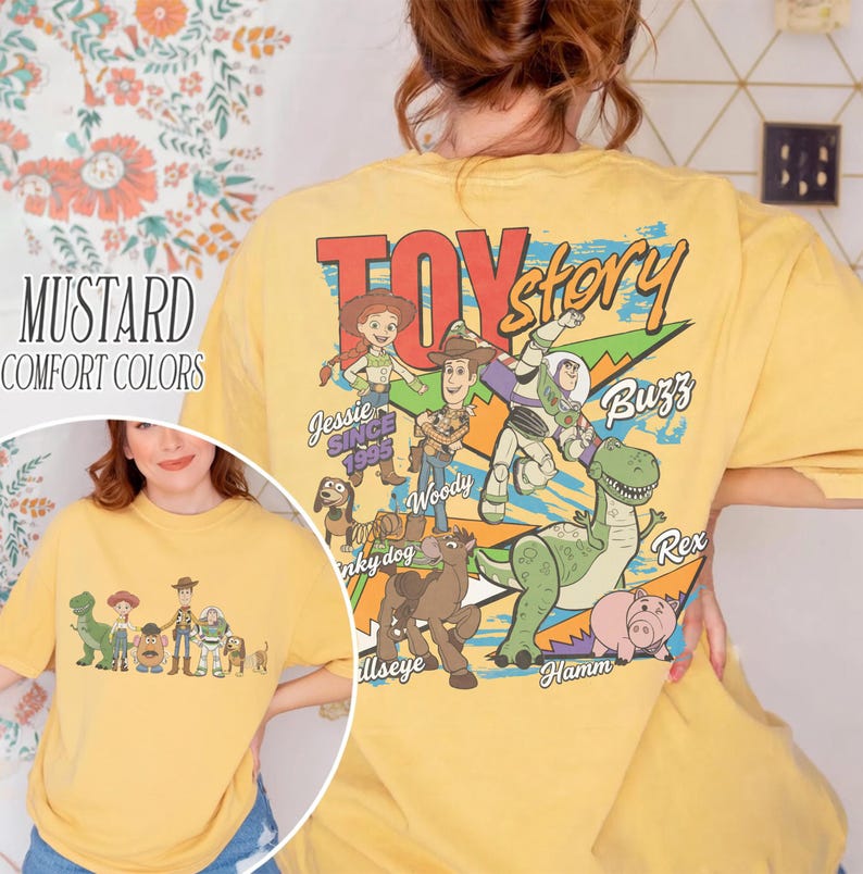 Może przedstawiać: Musztardowa koszulka comfort colors z grafiką postaci z Toy Story. Projekt zawiera Woody'ego, Buzz Lightyeara, Jessie, Rexa i Hamma. Tekst "Toy Story" jest wydrukowany na g&oacute;rze.