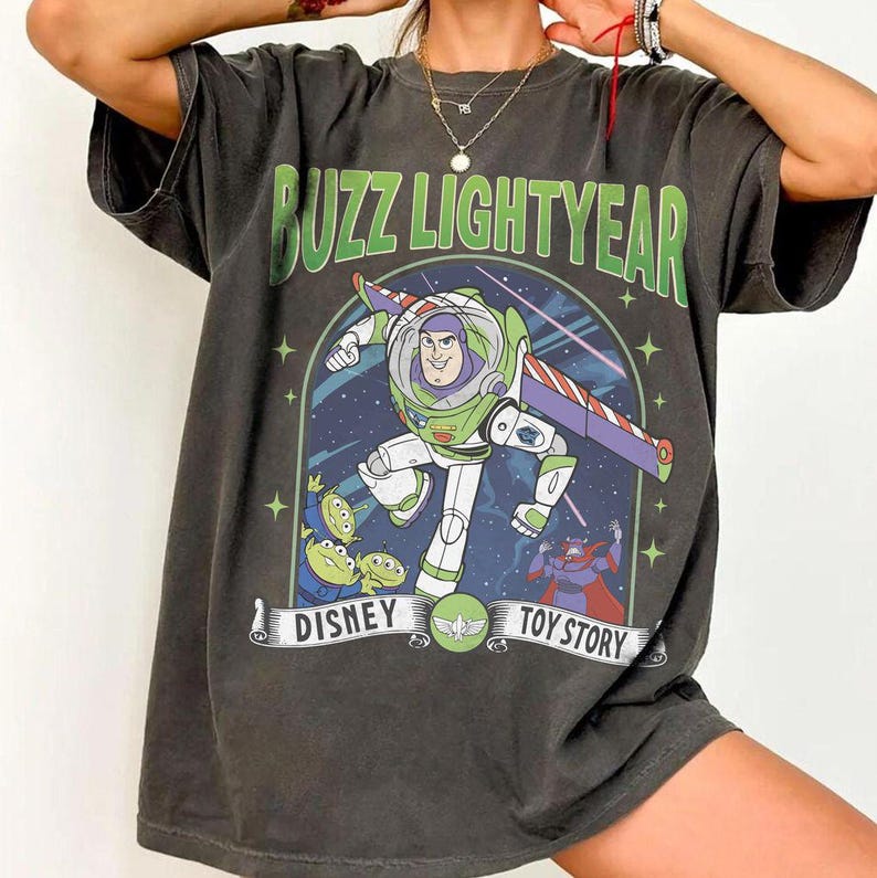 May include: Dark grey t-shirt featuring Buzz Lightyear from Disney's Toy Story. The graphic includes Buzz in his spacesuit, aliens, and the text "Buzz Lightyear" and "Disney Toy Story".