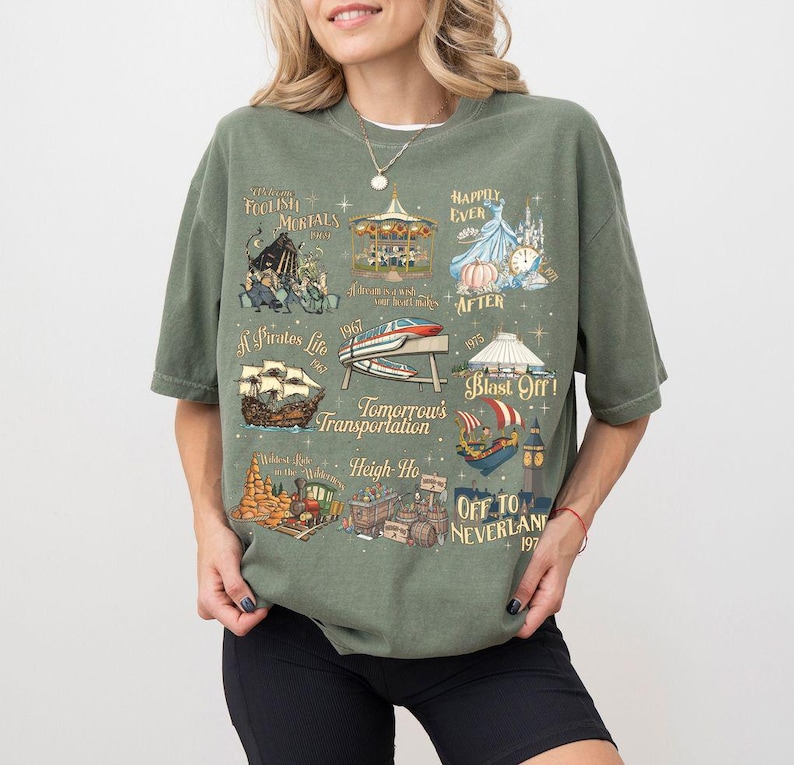 K&ouml;nnte beinhalten: Olivgr&uuml;nes T-Shirt mit Vintage-Design, das Themenpark-Illustrationen und S&auml;tze wie "Foolish Mortals" und "Off to Neverland" zeigt. Das Shirt zeigt ein Karussell, ein Piratenschiff und eine Rakete, mit dem Jahr 1967.