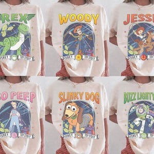 May include: Cream-coloured t-shirts featuring characters from Disney's Toy Story. Each shirt displays a different character: Rex, Woody, Jessie, Bo Peep, Slinky Dog, and Buzz Lightyear, with the Disney and Toy Story logos.