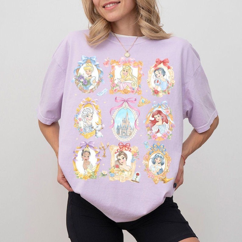 May include: A light purple t-shirt featuring nine framed portraits of Disney princesses. Each portrait is surrounded by floral and bow accents. The princesses are depicted in their iconic outfits and hairstyles. The shirt is a comfortable, casual style.