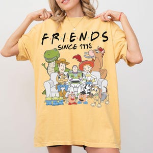 K&ouml;nnte beinhalten: Eine wei&szlig;e Keramik-Tasse mit schwarzem Henkel und dem Text "But First, Coffee" in fetter, schwarzer Schrift. Die Tasse steht vor einem verschwommenen Hintergrund, der eine gem&uuml;tliche Umgebung andeutet.