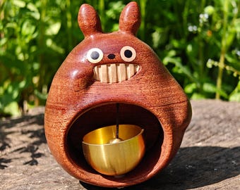 Timbre de puerta artesanal de madera de ébano con diseño de Totoro sonriente y campanilla magnética de latón.