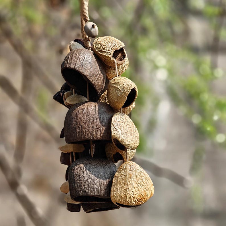 Puede incluir: Un m&oacute;vil de viento colgante compuesto por materiales naturales y texturizados. El m&oacute;vil presenta una serie de elementos en forma de campana en tonos marr&oacute;n, beige y tostado, suspendidos de un cord&oacute;n tejido. El dise&ntilde;o incorpora diversas formas y texturas org&aacute;nicas.