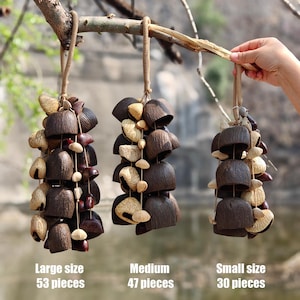 Könnte beinhalten: Drei hängende Windspiele aus natürlichen Materialien. Die Windspiele sind an einem Ast aufgehängt. Die Windspiele bestehen aus dunkelbraunen, beigen und rotbraunen Teilen. Der Text unten lautet "Large size 53 pieces", "Medium 47 pieces" und "Small size 30 pieces".