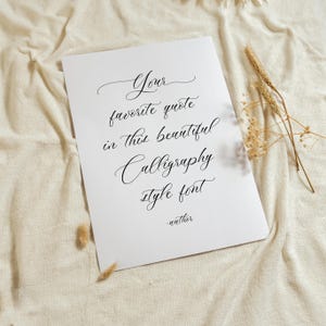 Może przedstawiać: Biały prostokątny wydruk z czarnym tekstem kaligraficznym o treści: Your favorite quote in this beautiful Calligraphy style font -author. Wydruk jest umieszczony na teksturowanej tkaninie w kolorze złamanej bieli z suszonymi kłosami pszenicy.