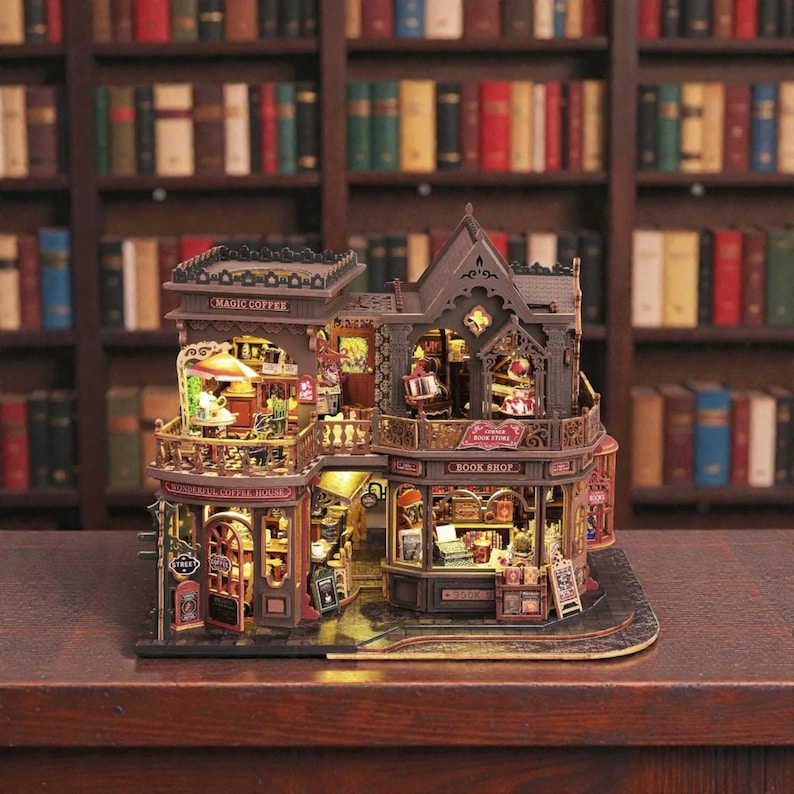 Pu&ograve; includere: Modello in miniatura dettagliato di una caffetteria e libreria. Il modello presenta intricati dettagli architettonici, calda illuminazione interna e insegne con la scritta "Magic Coffee" e "Book Shop". Il modello &egrave; ambientato sullo sfondo di librerie.