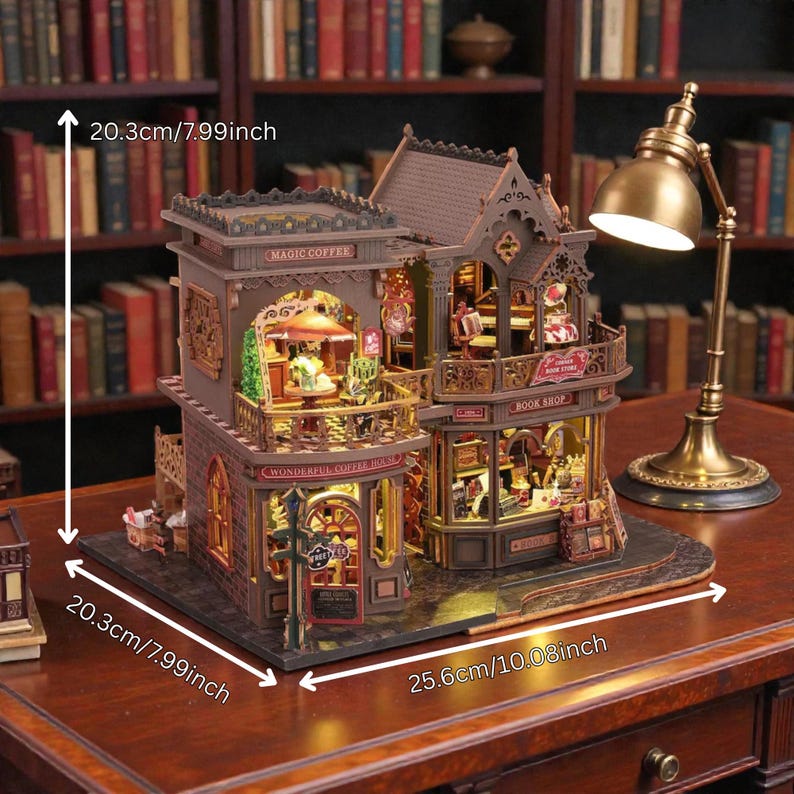 Pu&ograve; includere: Un modello in miniatura dettagliato di una caffetteria e libreria, alto 20,3 cm e largo 25,6 cm. Il modello presenta intricati dettagli architettonici, con le parole "MAGIC COFFEE", "WONDERFUL COFFEE HOUSE" e "BOOK SHOP" visibili.