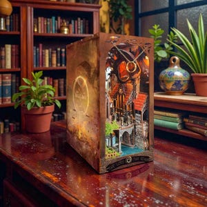 May include: A detailed, laser-cut wooden book-shaped lamp featuring a scene from The Lord of the Rings. The lamp has a warm, inviting glow, with intricate architectural details and a golden ring pendant. The book is displayed on a wooden table.