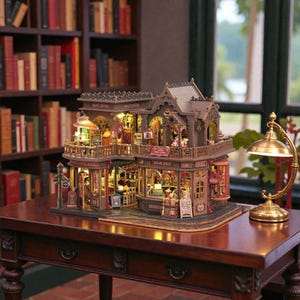 Puede incluir: Una maqueta en miniatura detallada de una librería y cafetería, con intrincados detalles arquitectónicos y una cálida iluminación interior. El modelo presenta balcones, señalización y pequeñas figuras, creando una escena encantadora y acogedora.