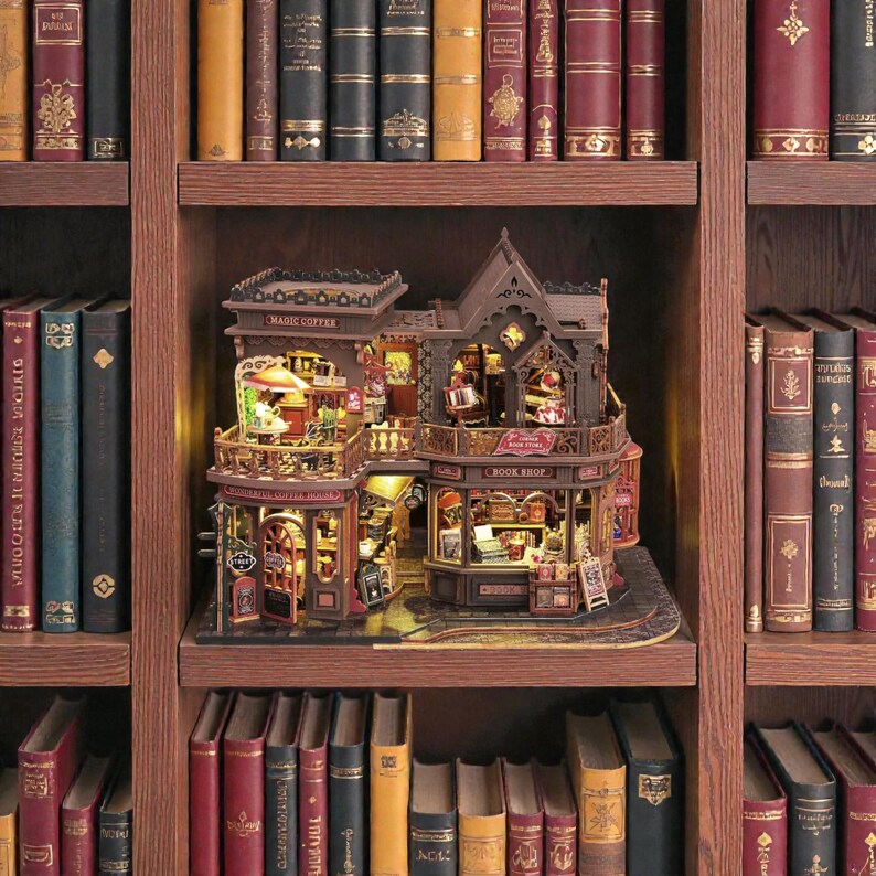 Pu&ograve; includere: Un modello in miniatura dettagliato di una libreria e caffetteria, con i testi "MAGIC COPPER" e "BOOK SHOP" visibili. Il modello &egrave; marrone con illuminazione interna, posto su uno scaffale circondato da libri di vari colori e dimensioni.